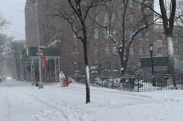 A man clears out snow with a snowblower in a residential section of Brooklyn Heights on Saturday.
